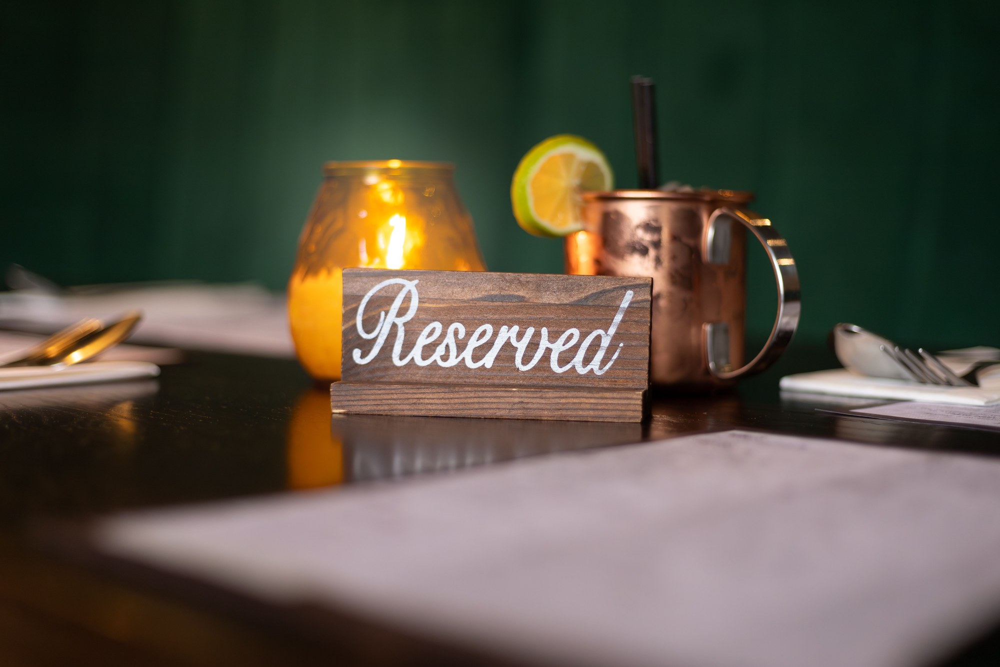 Cartel de madera de reservado sobre la mesa, con la vela encendida