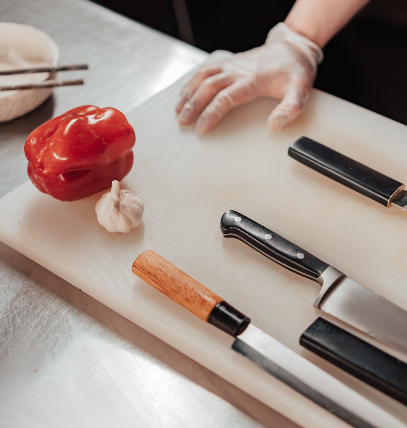 Pimiento, ajo y cuchillos sobre una tabla de corte blanca
